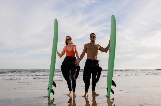 Una pareja de jóvenes surfistas románticos posando juntos en la playa en verano