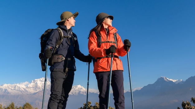 Una pareja de jóvenes viajeros haciendo senderismo en el mirador de Poon Hill en Ghorepani Nepalx9