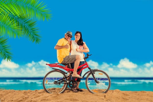 Pareja de jubilados asiáticos indios con su bicicleta o bicicleta en la playa, efecto de mal humor