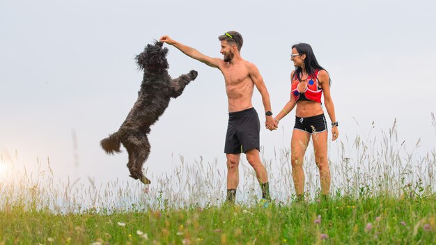 Pareja juega con perro en la naturaleza