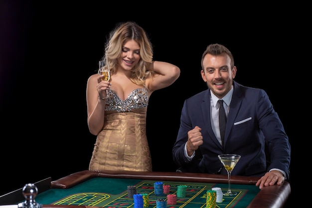 Pareja de juegos de azar en la mesa de la ruleta en el casino. Fondo negro. Emoción. Riesgo. Suerte