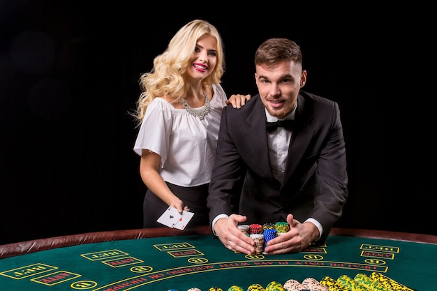 Pareja jugando al póquer en la mesa. La chica rubia y un chico de traje. feliz victoria