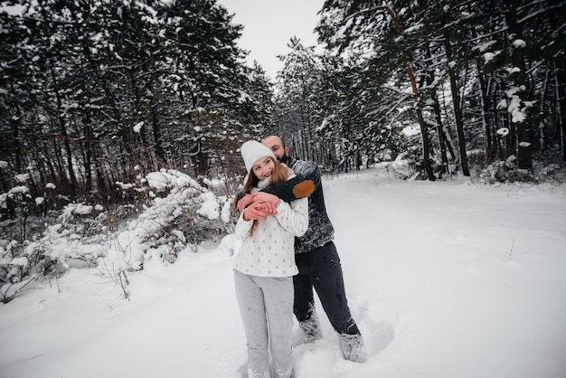 Pareja jugando con nieve en el bosque.