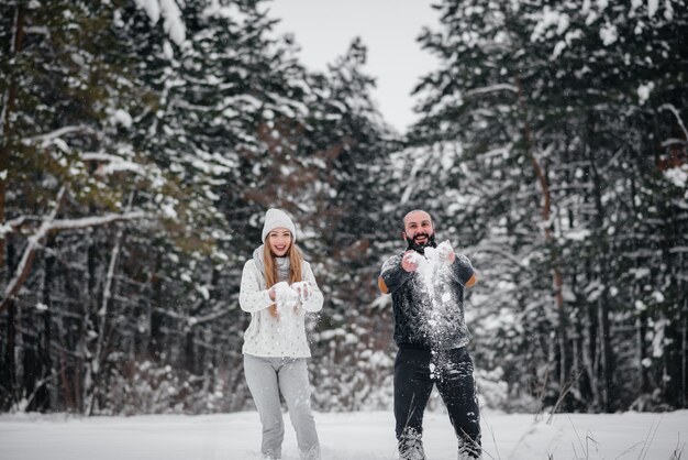 Pareja jugando con nieve en el bosque