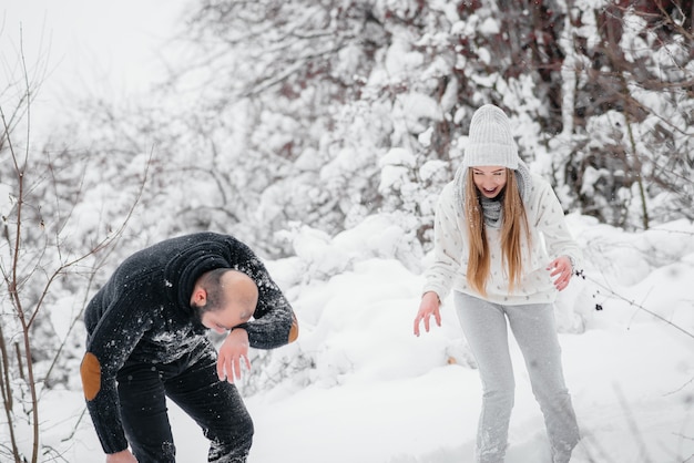 Pareja jugando con nieve en el bosque