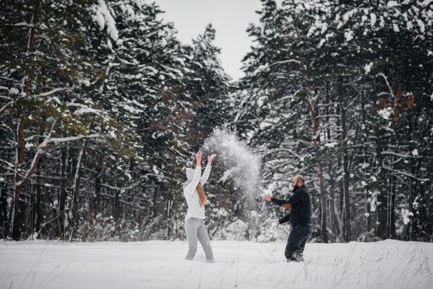 Pareja jugando con nieve en el bosque