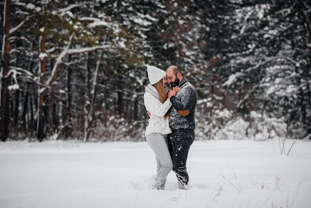 Pareja jugando con nieve en el bosque