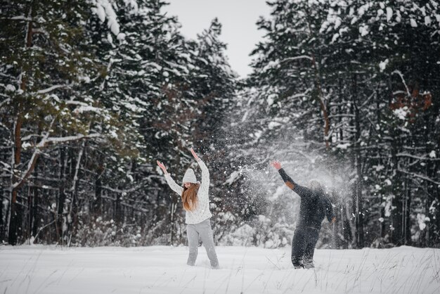 Pareja jugando con nieve en el bosque