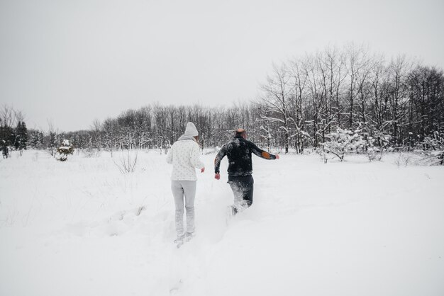 Pareja jugando con nieve en el bosque