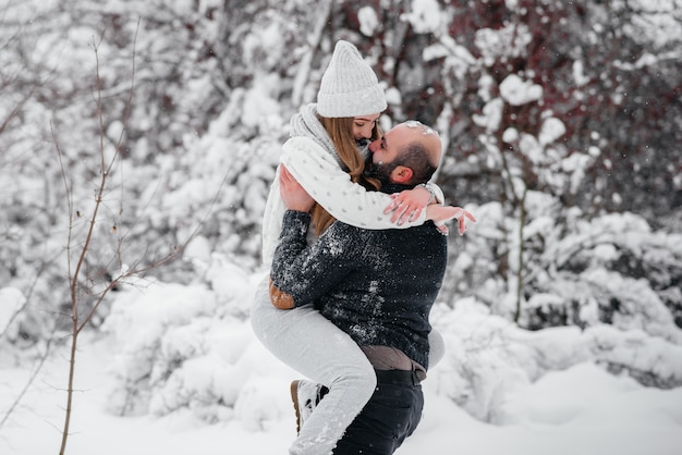 Pareja jugando con nieve en el bosque