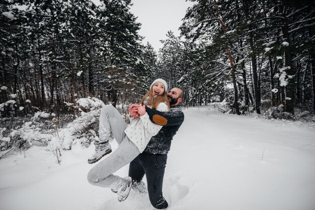 Pareja jugando con nieve en el bosque.