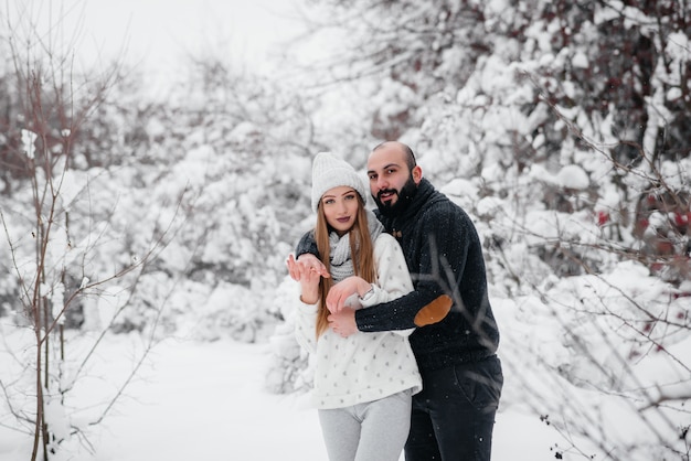 Pareja jugando con nieve en el bosque