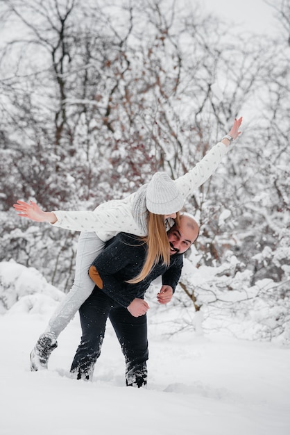 Pareja jugando con nieve en el bosque.