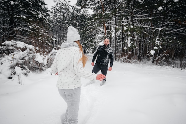 Pareja jugando con nieve en el bosque.