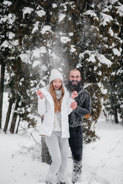 Pareja jugando con nieve en el bosque.