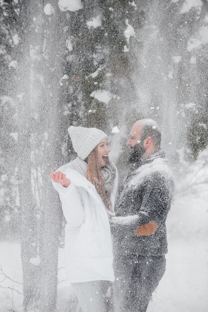 Pareja jugando con nieve en el bosque.