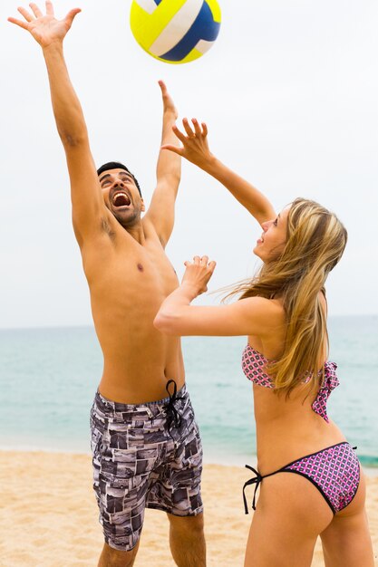 Pareja jugando con una pelota en la playa