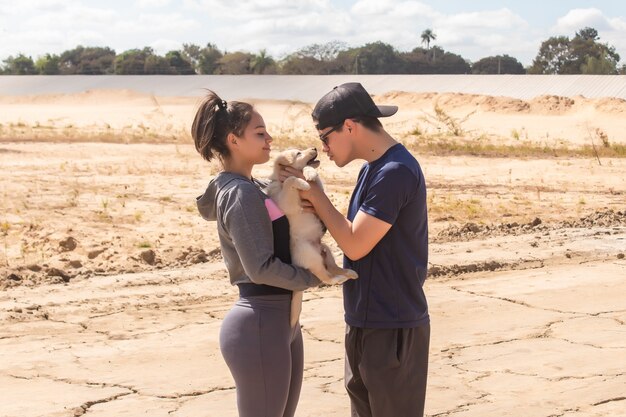 Pareja jugando con su cachorro en la playa.