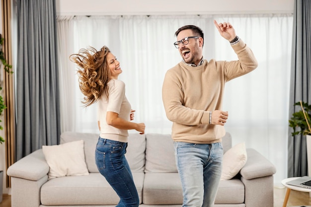 Una pareja juguetona baila en el salón de su nuevo apartamento