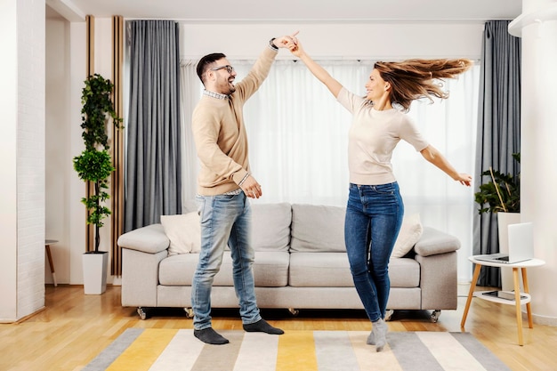 Una pareja juguetona bailando juntos en su nuevo hogar