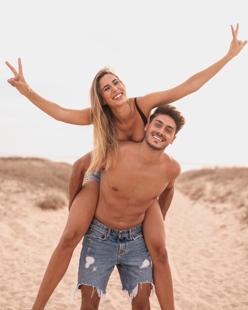 Foto pareja juguetona caballito en la playa