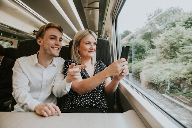 Pareja junto a la ventana del tren tomando fotos del paisaje