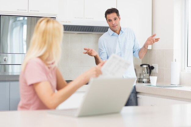 Pareja con laptop y bill en la cocina