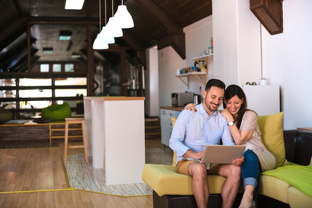 Foto pareja con laptop sentada en el sofá en su sala de estar