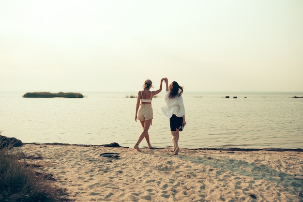 Pareja de lesbianas divertirse en la playa Hermosas amigas felices relajarse cerca del mar