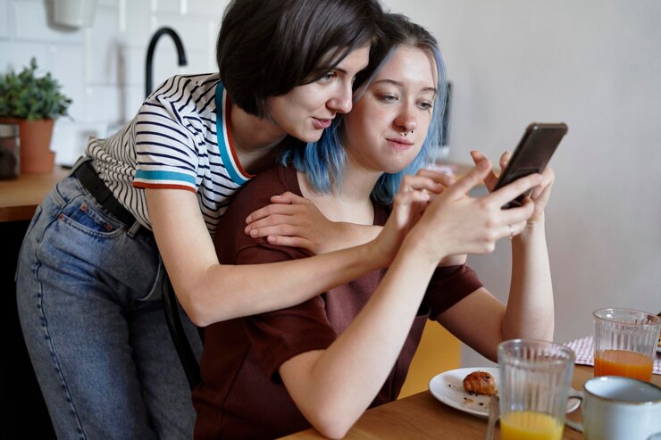 Foto una pareja de lesbianas mirando algo en el teléfono durante el desayuno.