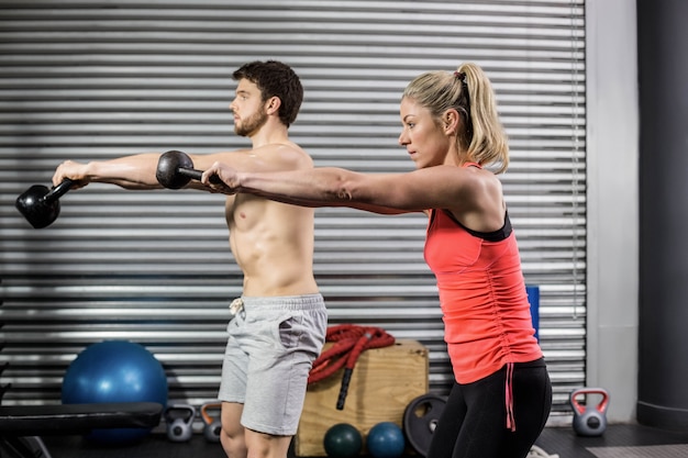 Pareja levantando pesas juntos en el gimnasio de crossfit