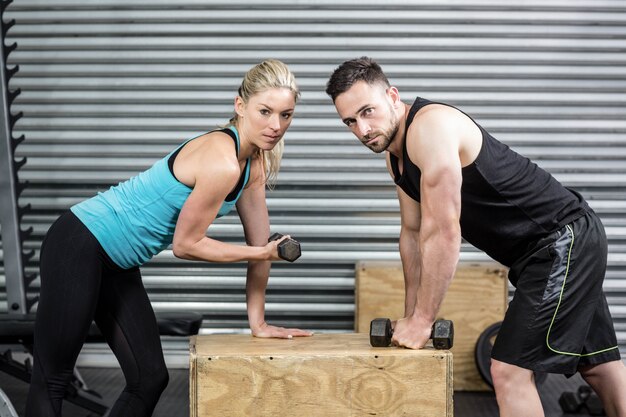 Pareja levantando pesas juntos en el gimnasio de crossfit