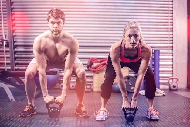 Foto pareja levantando pesas juntos en el gimnasio de crossfit