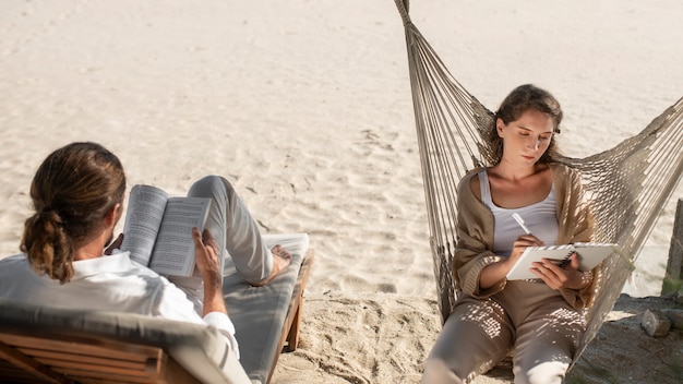 Pareja leyendo libros en la playa durante las vacaciones