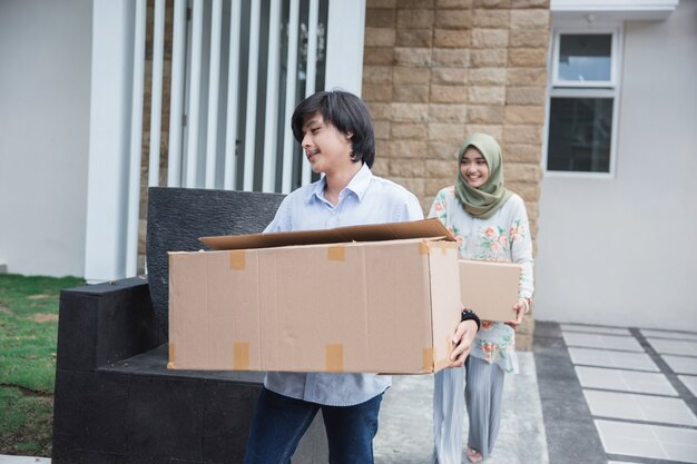 Pareja lleva caja de cartón para mudarse a casa nueva