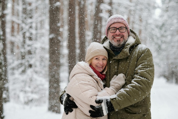 Pareja madura alegre en ropa de invierno mirando a la cámara