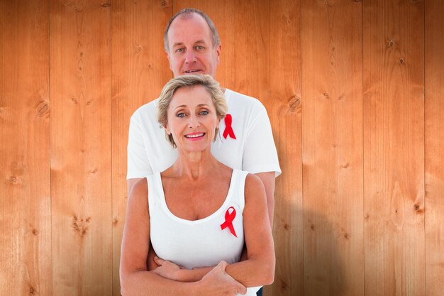 Foto pareja madura apoyando la concienciación sobre el sida juntos contra tablones de madera