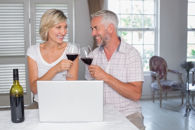 Pareja madura brindando copas de vino en casa