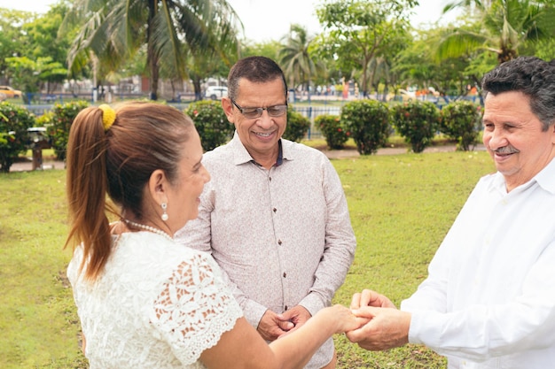 Pareja madura casándose por el sacerdote durante el día soleado