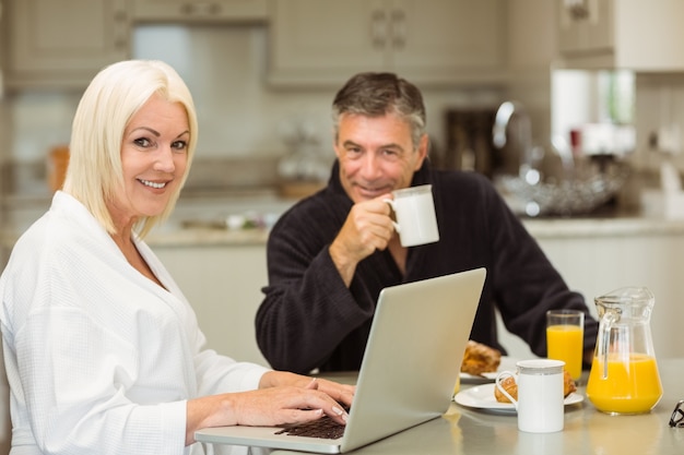 Pareja madura desayunando juntos mujer usando laptop