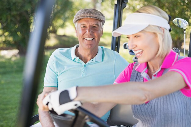 Pareja madura disfrutando en buggy de golf