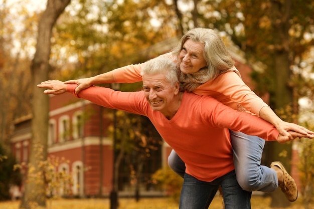 Pareja madura divirtiéndose en el parque de otoño