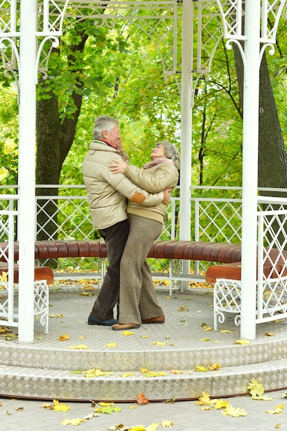 Pareja madura divirtiéndose en el parque de otoño