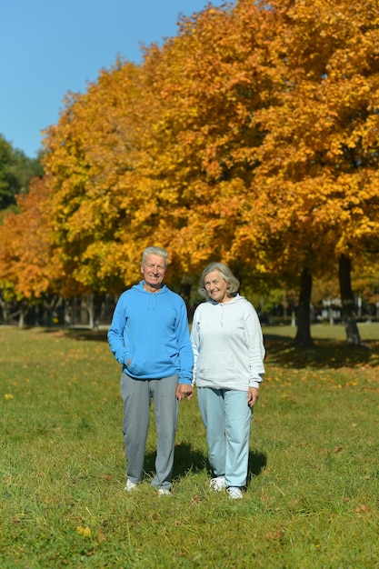 Pareja madura divirtiéndose en el parque de otoño