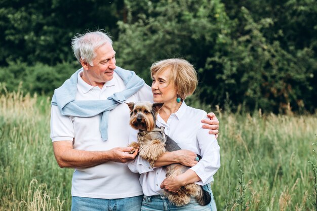 Una pareja madura está caminando con un perro en un parque