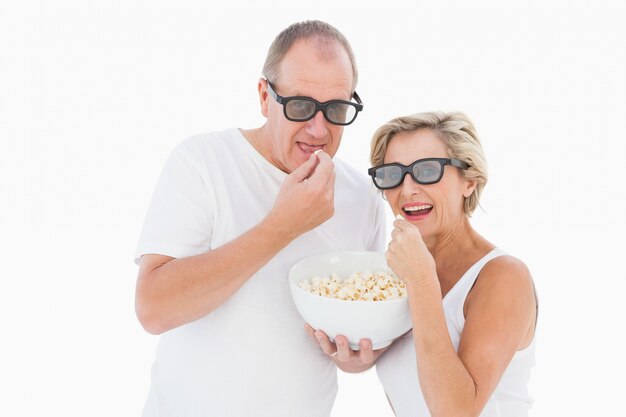 Pareja madura con gafas 3d comiendo palomitas de maíz