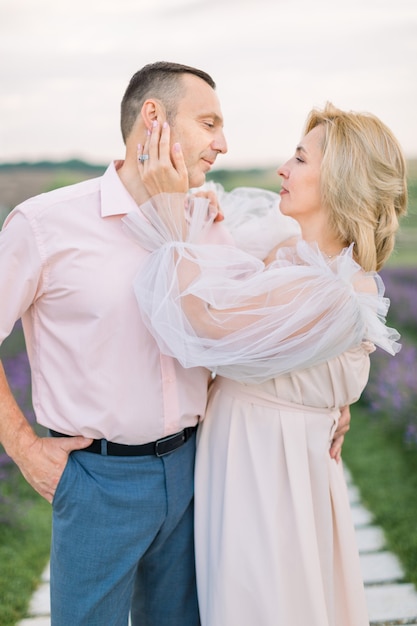 Pareja madura, mirándose con ternura y amor, juntos en el campo de lavanda