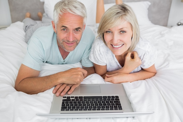 Pareja madura relajado usando la computadora portátil en la cama