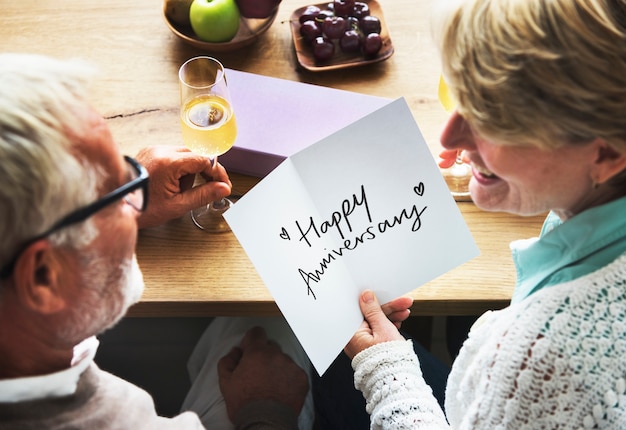 Pareja madura sosteniendo una tarjeta de aniversario