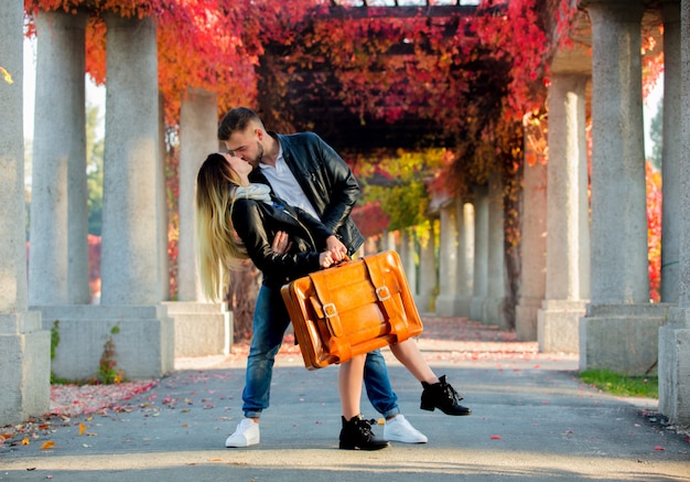 Pareja con maleta en callejón en otoño temporada